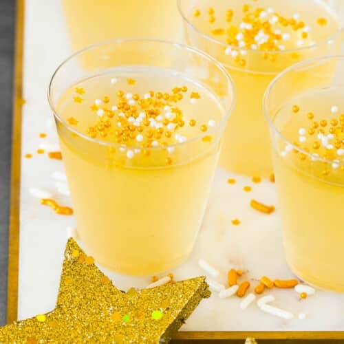 Champagne Jello shots on a marble tray with sprinkles on top.