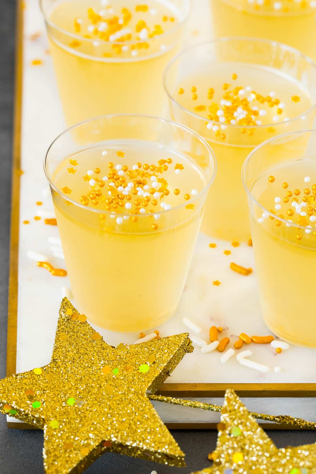 Champagne Jello shots on a marble tray with sprinkles on top.
