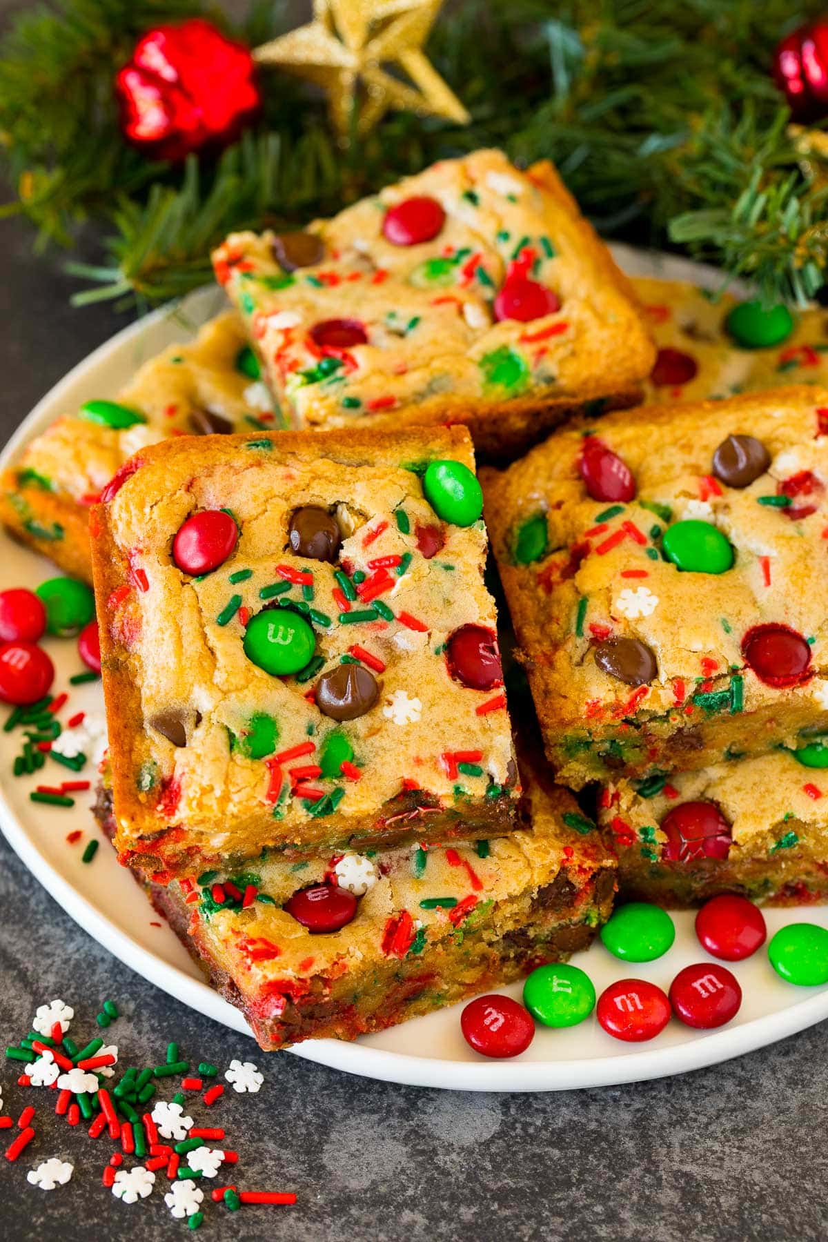Christmas cookie bars on a plate with sprinkles and M&M candies as garnish.
