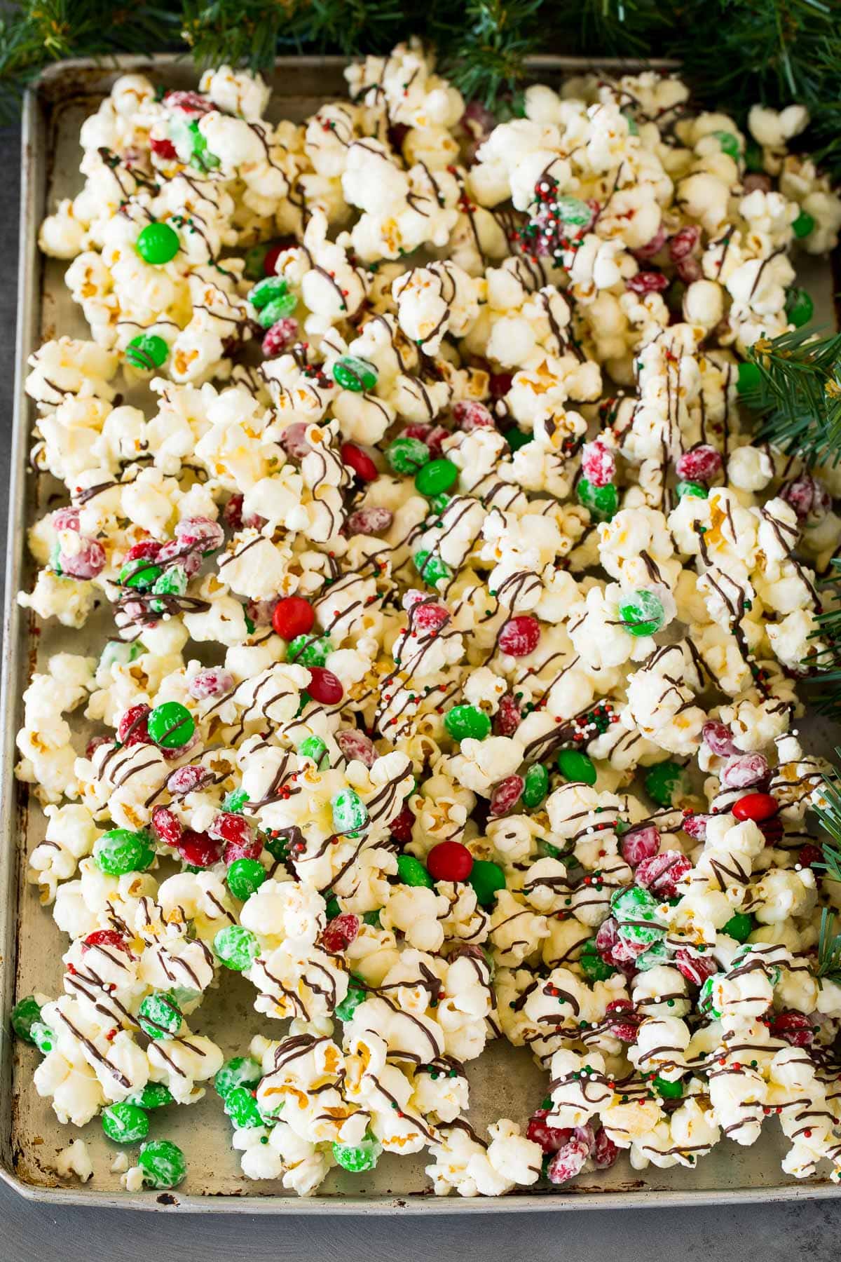 Christmas popcorn on a sheet pan topped with sprinkles and chocolate.