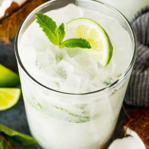 A coconut mojito in a glass, garnished with fresh mint and a lime wedge.