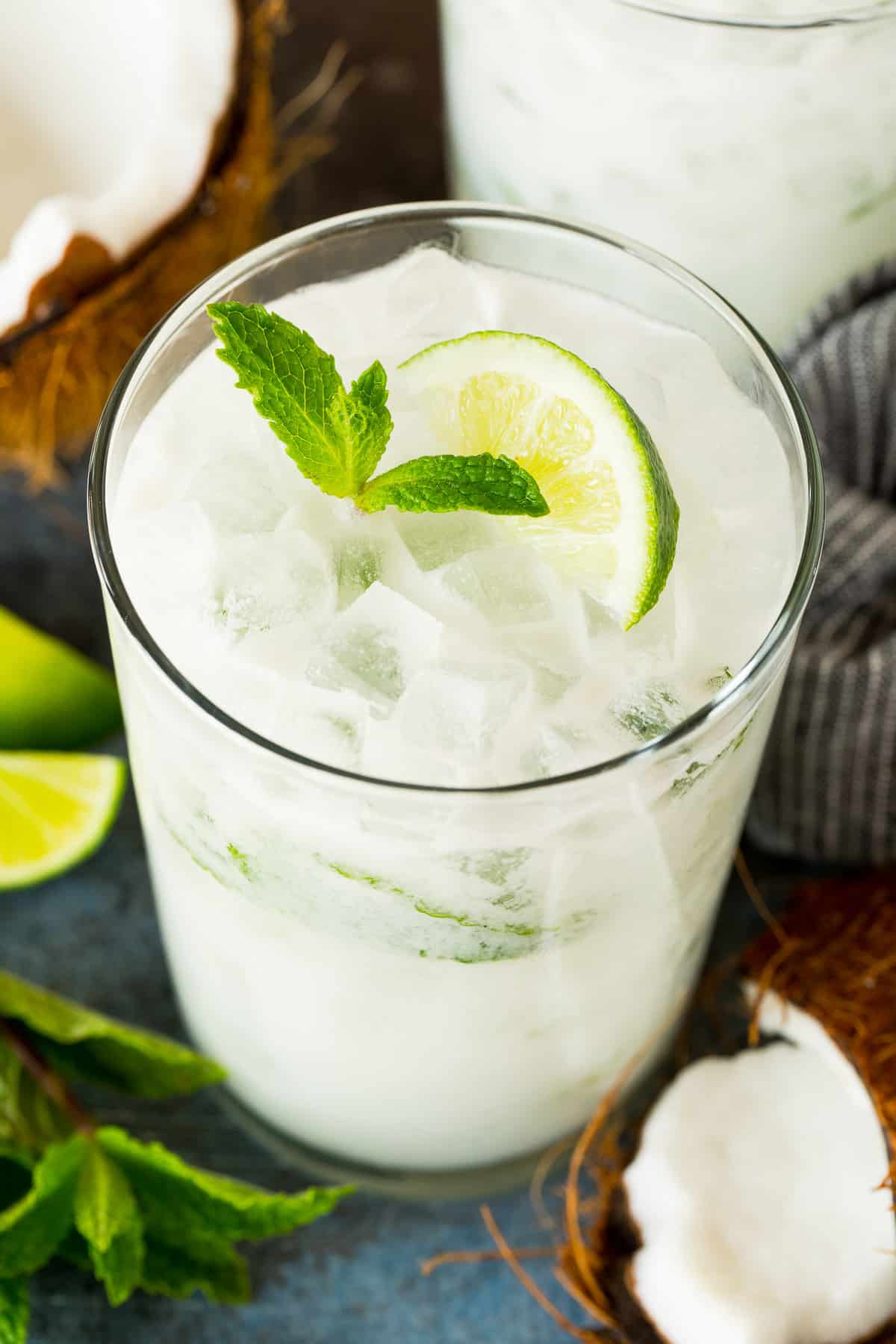 A coconut mojito in a glass, garnished with fresh mint and a lime wedge.