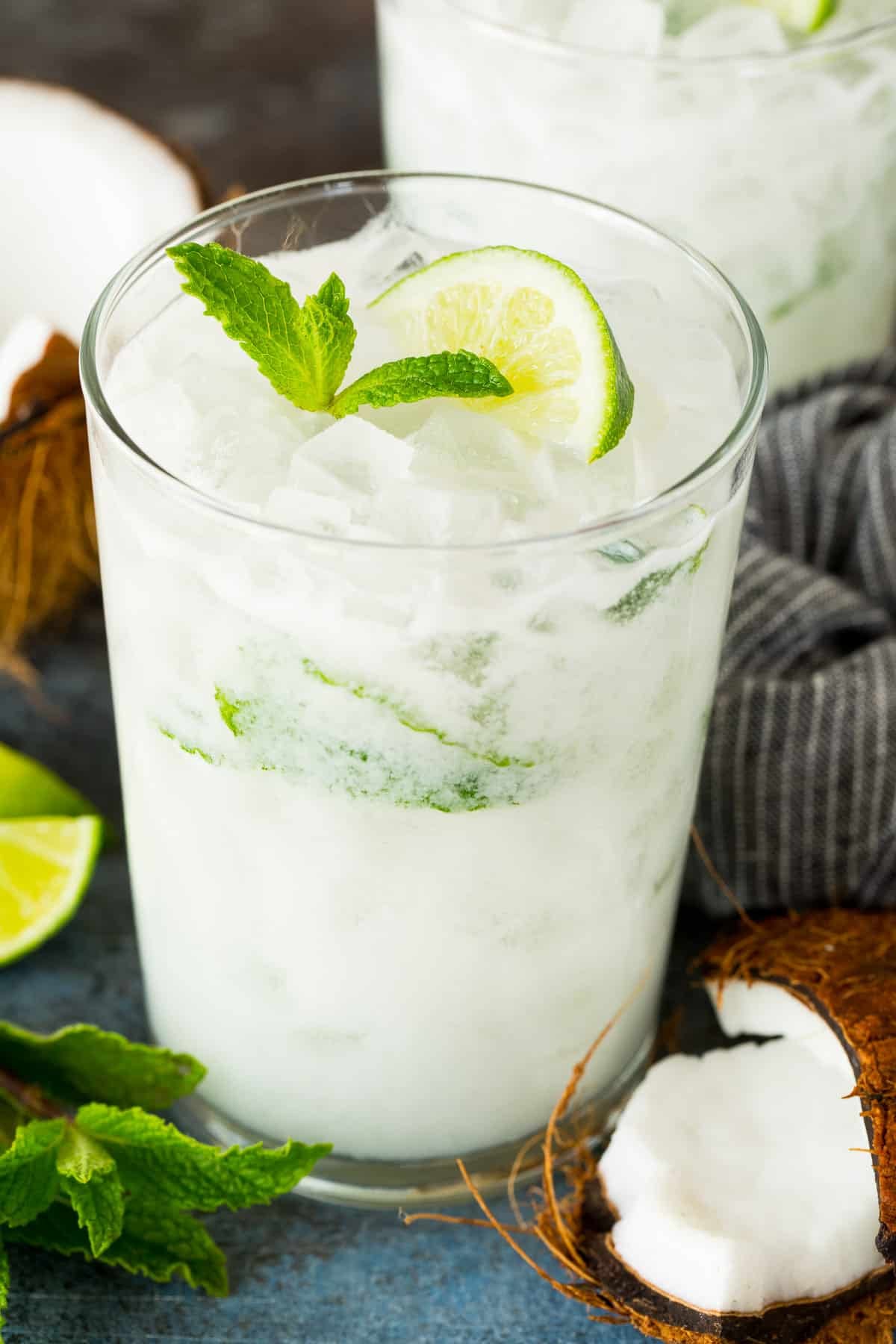 A glass of coconut mojito cocktail topped with a lime slice and mint.