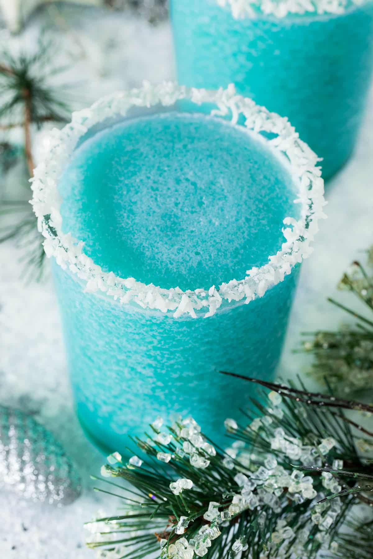 A glass of Jack Frost cocktail surrounded by winter greenery.