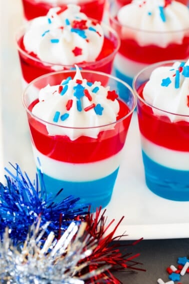 Red white and blue Jello shots topped with whipped cream and sprinkles.