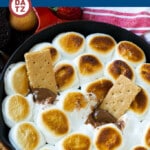 A skillet of s'mores dip with graham crackers and fruit.