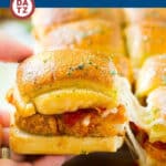 Chicken parmesan sliders with melty cheese being lifted off a sheet pan.