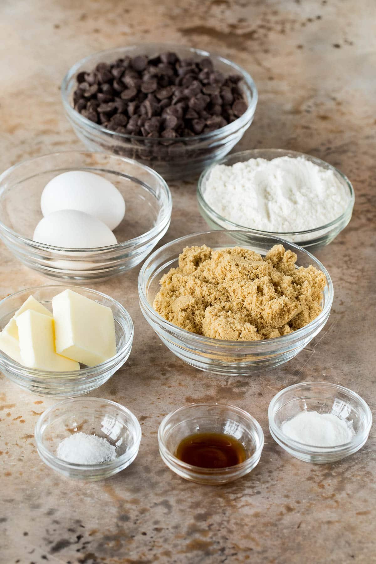 Bowls of ingredients including brown sugar, chocolate chips., flour, butter and eggs.