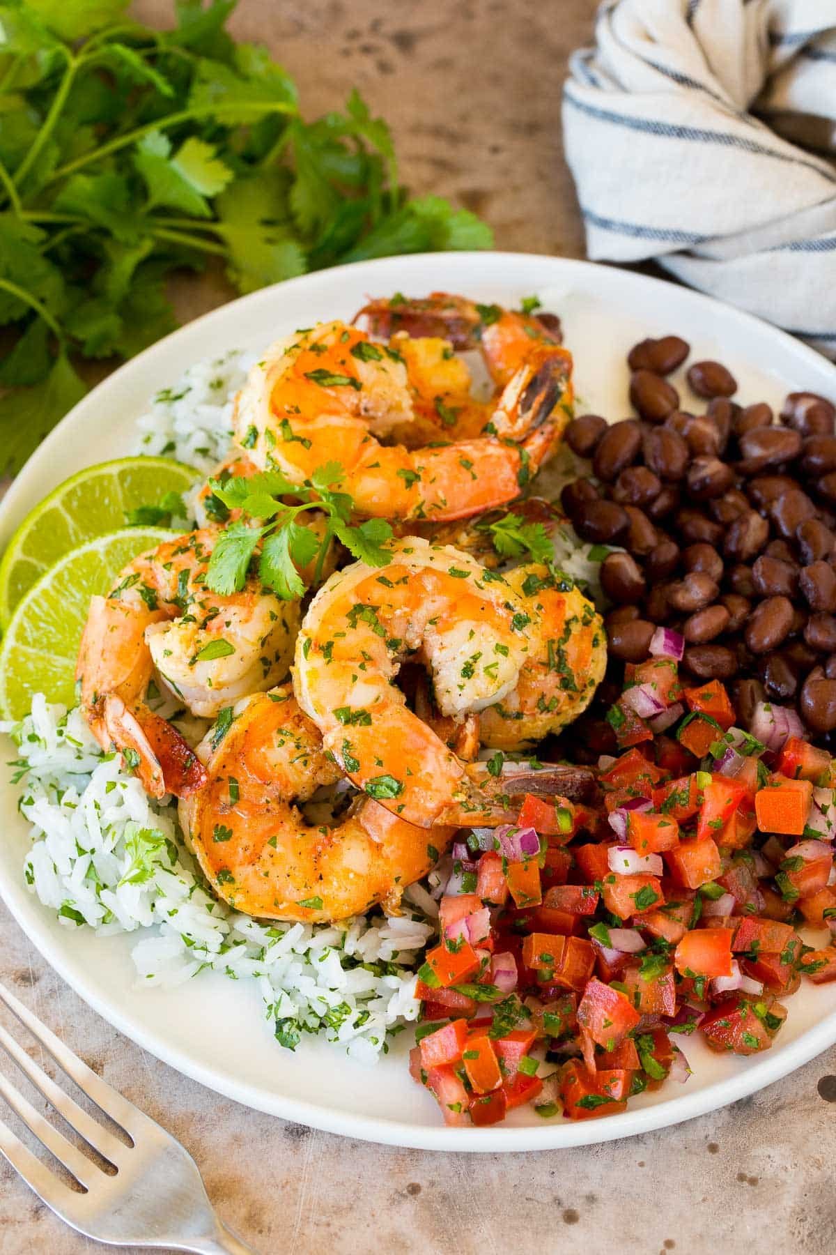 Cilantro lime shrimp on a plate with rice, beans and salsa.