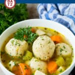 A bowl of matzo ball soup with chicken, vegetables and fluffy matzo balls.