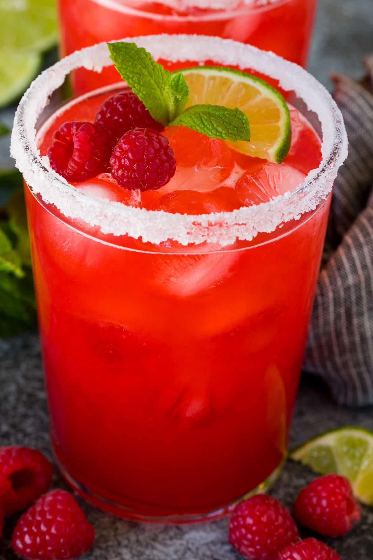 A raspberry margarita with a sugar rim and fresh berries on top.