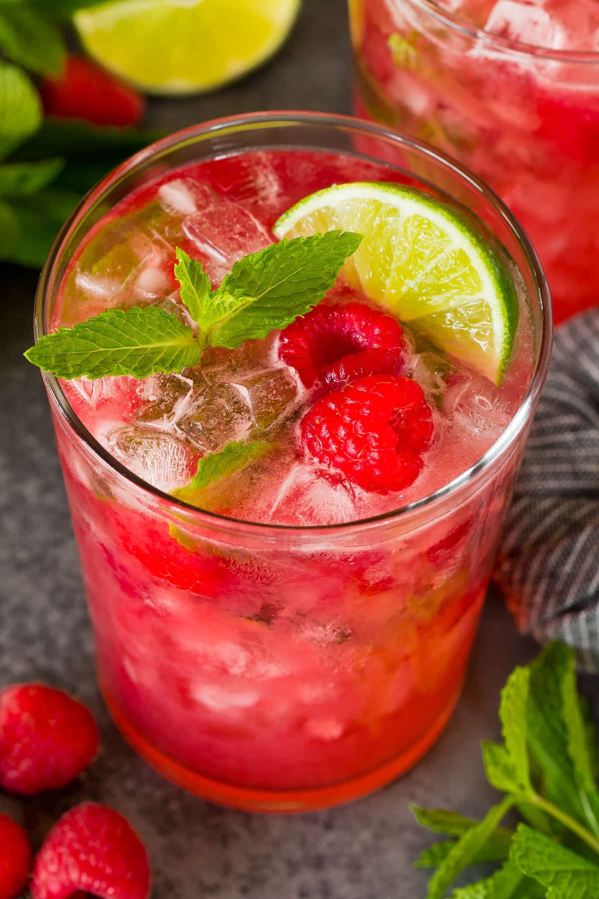 A raspberry mojito topped with fresh berries and a mint sprig.