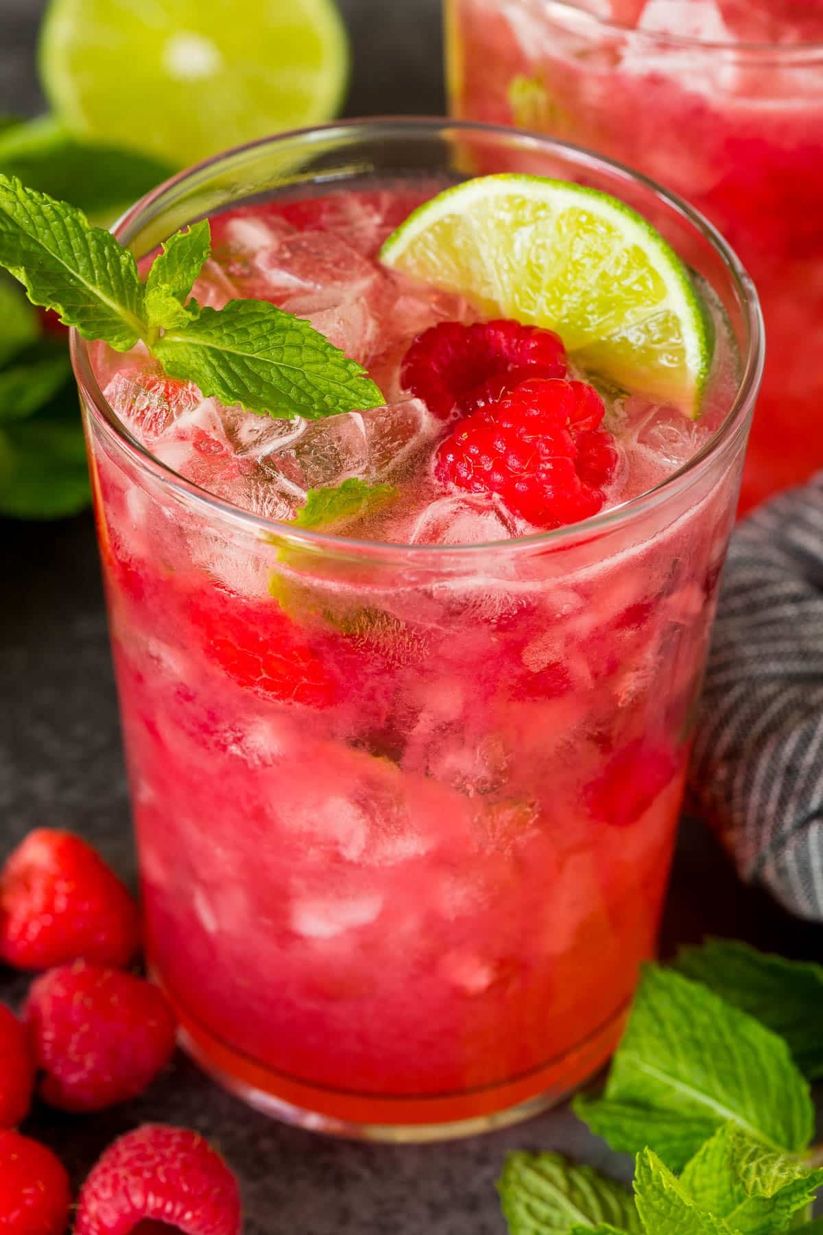 A cup of raspberry mojito with a garnish of lime and raspberries.