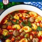A pot of tortellini soup with sausage and vegetables in a savory tomato broth.