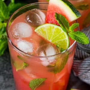 A cup of watermelon mojito topped with fresh mint, lime and fresh watermelon.