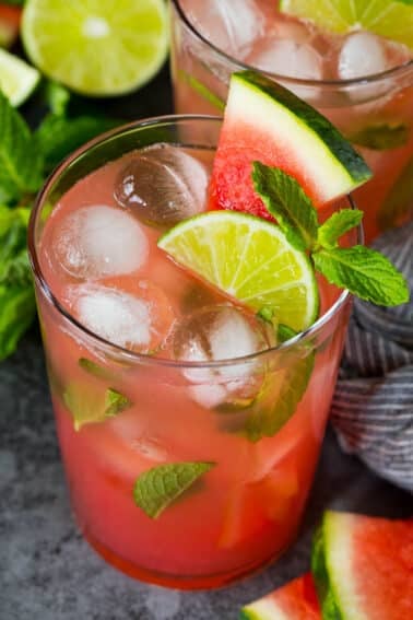 A cup of watermelon mojito topped with fresh mint, lime and fresh watermelon.