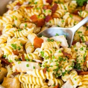 A skillet of chicken bacon ranch pasta with a serving spoon in it.