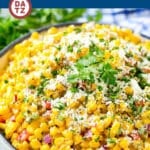 A bowl of Mexican corn salad topped with cotija cheese and cilantro.