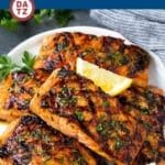 A plate of grilled salmon fillets garnished with parsley and lemon wedges.