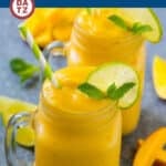 A mug of mango smoothie garnished with lime slices and fresh mint.