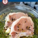 Two pork chops in a bowl of pork chop brine.