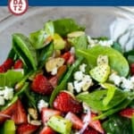 A bowl of strawberry spinach salad tossed in a poppy seed dressing.