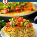 A slice of cheeseburger pie on a small plate topped with lettuce, tomatoes and bacon.