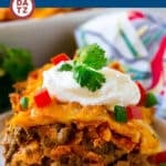 A slice of Dorito casserole topped with sour cream on a small plate.