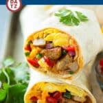 Two breakfast burritos stacked on a metal tray with eggs, sausage, beans and cheese.