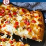 A slice of chicken alfredo pizza being lifted from a pan.