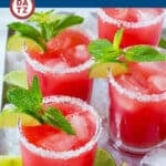 Several glasses of watermelon agua fresca garnished with mint and lime on a tray.