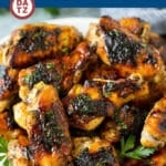 A plate piled high with grilled chicken wings and garnished with fresh parsley.