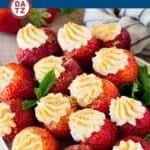 A bowl with cheesecake stuffed strawberries and mint leaves.