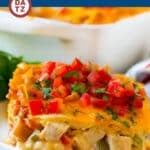 A slice of King Ranch Chicken casserole on a small plate topped with fresh diced tomatoes.